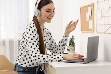 E-learning. Young woman using laptop during online lesson at table indoors