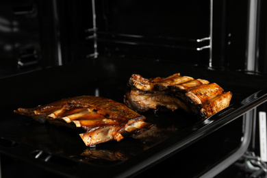 Photo of Delicious roasted ribs on baking sheet in oven