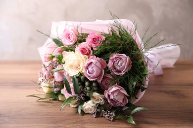 Photo of Beautiful bouquet with roses on wooden table