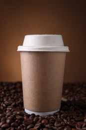 Photo of Coffee to go. Paper cup on roasted beans against brown background