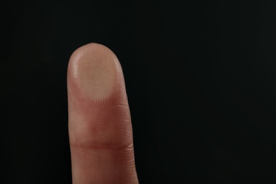 Photo of Woman pressing control glass of biometric fingerprint scanner on dark background, closeup. Space for text