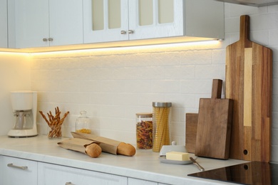 Photo of Countertop with modern coffee maker, wooden cutting boards and products in stylish kitchen