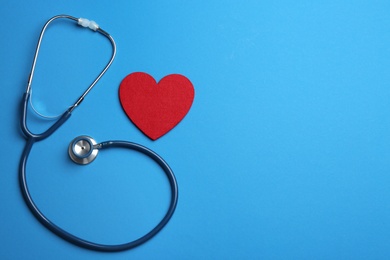 Photo of Stethoscope and red heart on blue background, flat lay with space for text. Health insurance concept