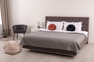 Photo of Large comfortable bed near light wall in simple room interior
