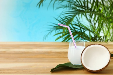 Photo of Composition with glass of coconut water on wooden table against blue background. Space for text
