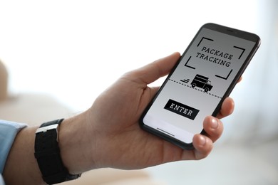 Image of Man tracking parcel via smartphone indoors, closeup