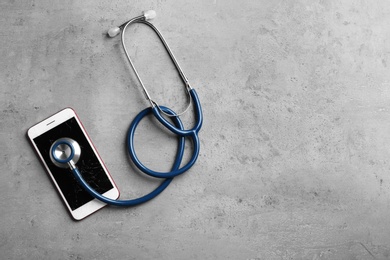 Photo of Modern smartphone with broken display, stethoscope and space for text on table, flat lay. Device repair service