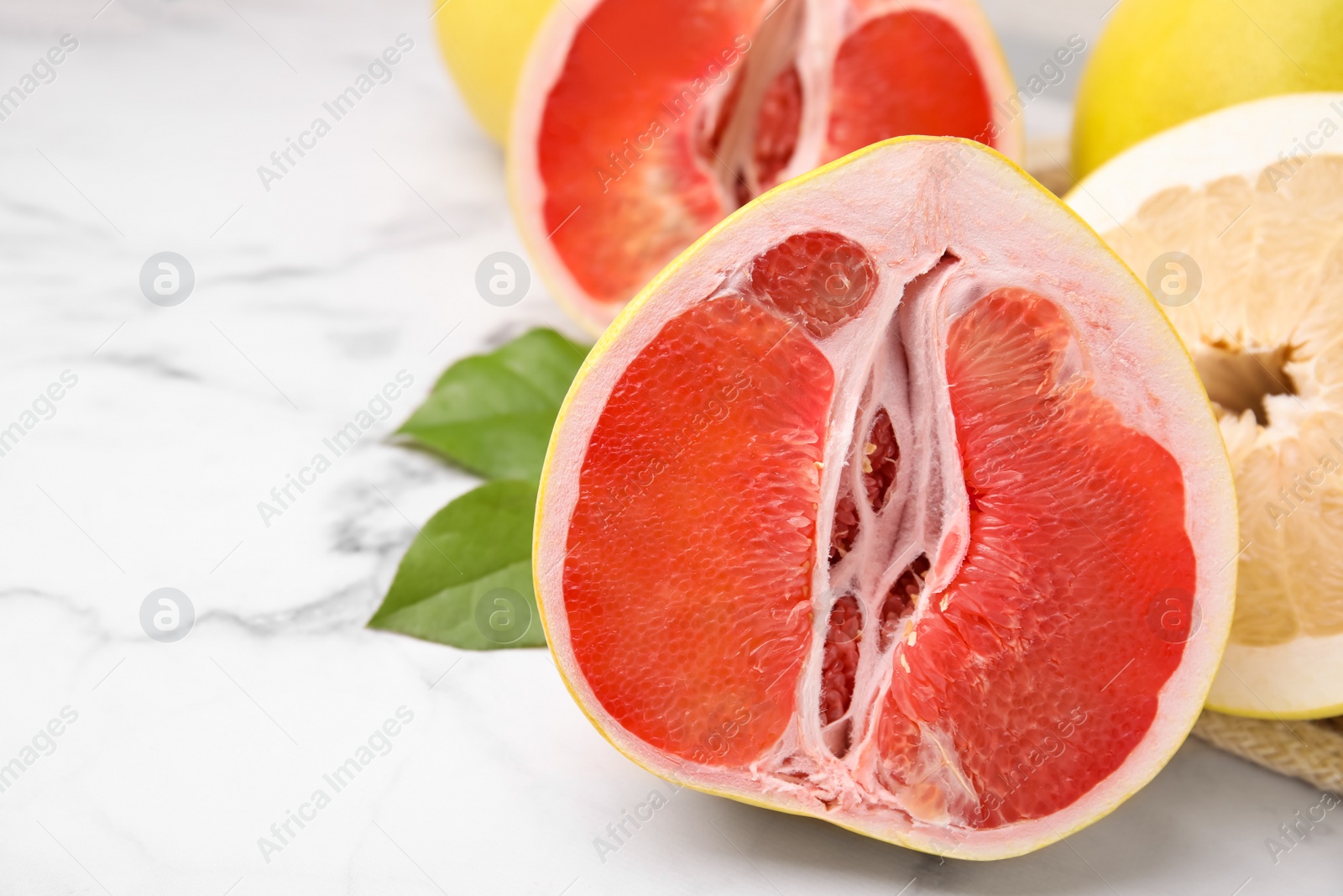 Photo of Different tasty pomelo fruits on white marble table, closeup. Space for text