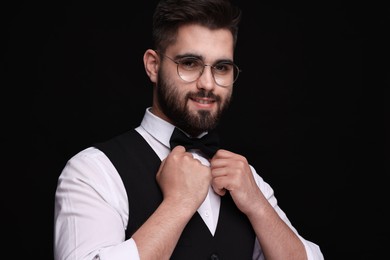 Photo of Portrait of smiling man in shirt and bow tie on black background