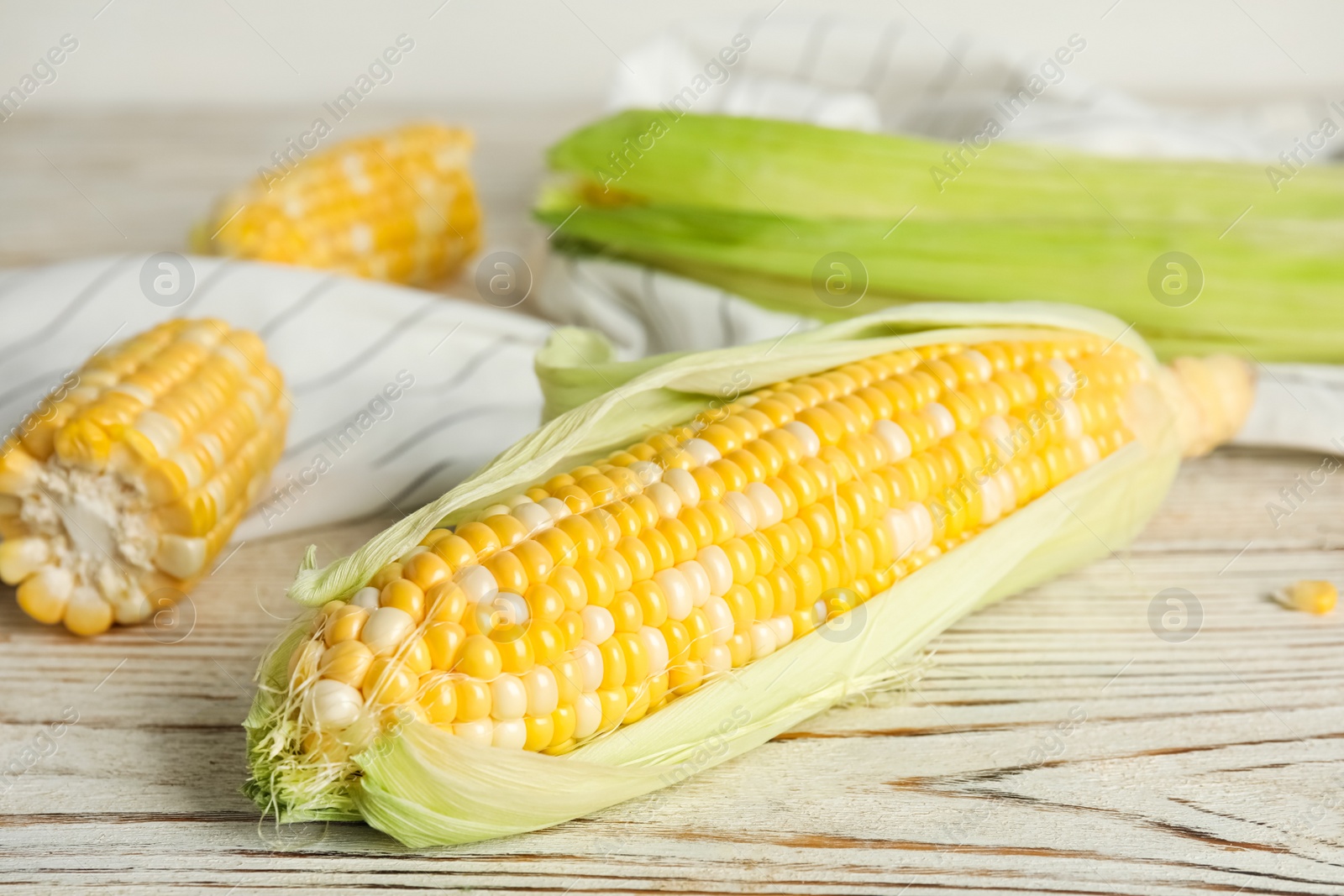 Photo of Tasty sweet corn cobs on white wooden table, closeup