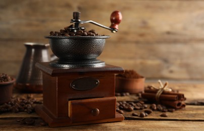 Photo of Vintage manual coffee grinder and beans on wooden table. Space for text
