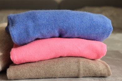Photo of Folded color sweaters on gray table, closeup