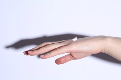 Photo of Woman with cream on her hand against white background, closeup