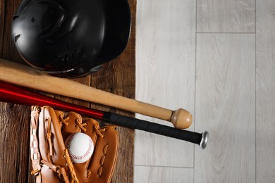 Photo of Baseball bats, batting helmet, leather glove and ball on wooden bench indoors, top view. Space for text