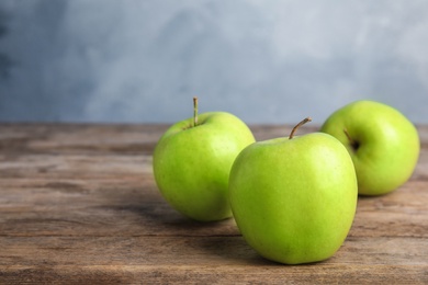 Photo of Fresh ripe green apples on wooden table against blue background, space for text