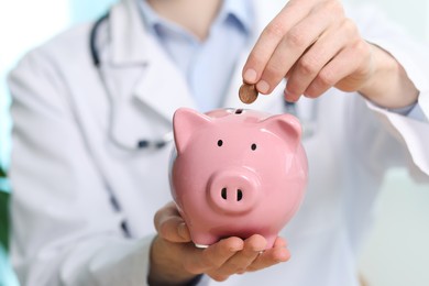 Photo of Doctor with piggy bank in hospital, closeup