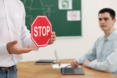 Photo of Teacher showing Stop road sign during lesson in driving school, closeup