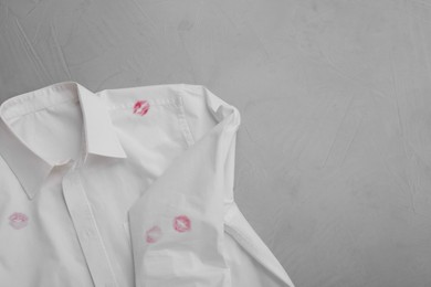 Photo of Men's shirt with lipstick kiss marks on light background, top view. Space for text