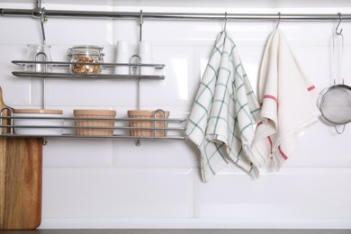 Photo of Different kitchen towels hanging on hook rod and shelves with ramekins indoors