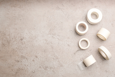 Photo of Sticking plaster rolls on stone background, flat lay. Space for text