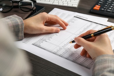 Photo of Woman working with accounting documents at wooden table, closeup