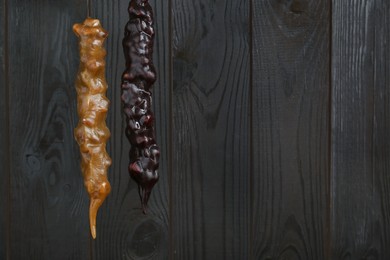 Photo of Delicious sweet churchkhelas hanging on wooden wall. Space for text