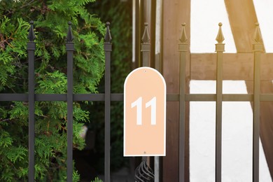 Photo of Plate with house number eleven hanging on iron fence outdoors