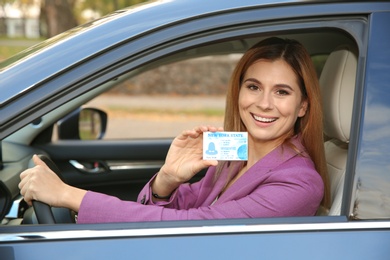 Photo of Happy woman holding driving license in car