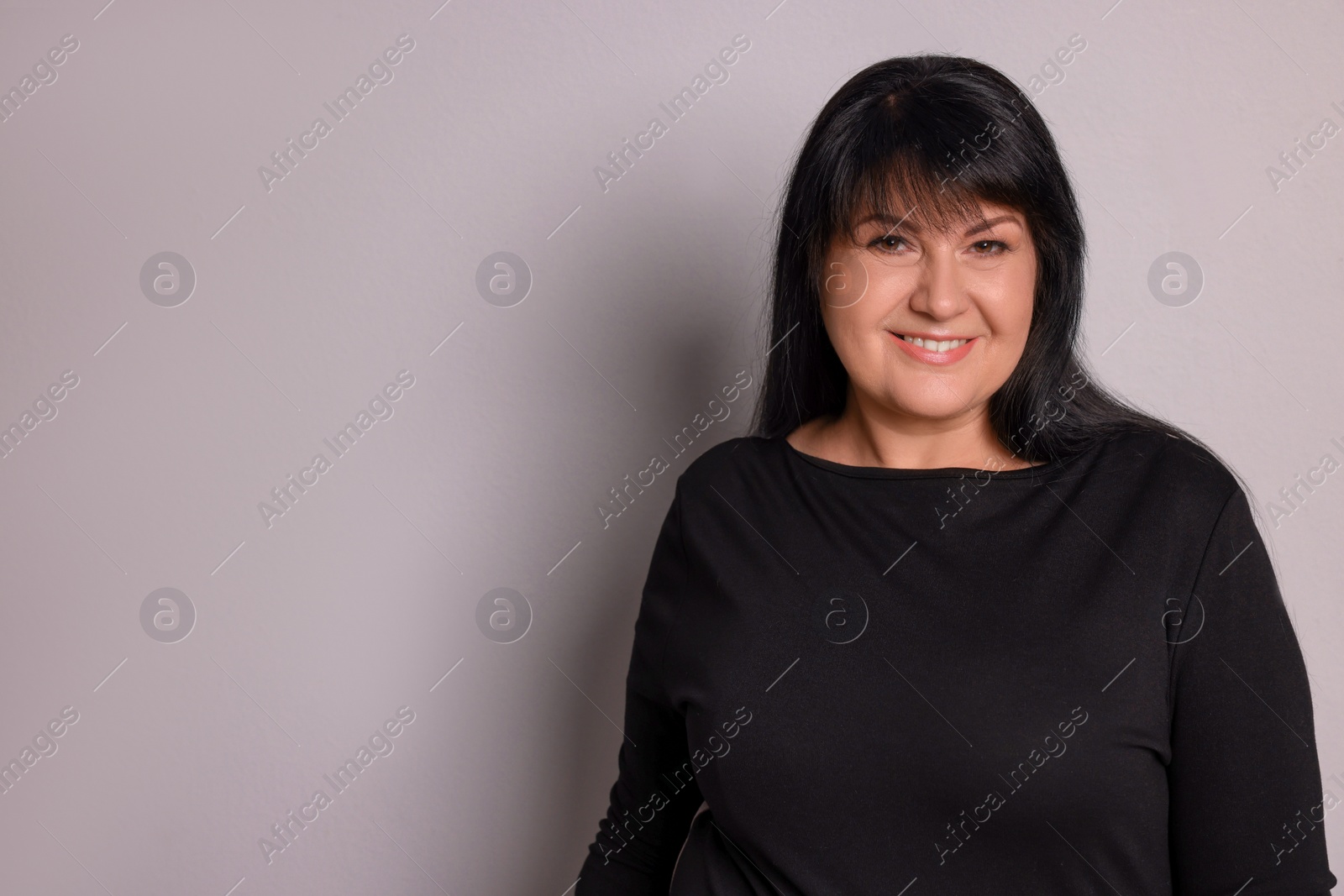 Photo of Beautiful overweight mature woman with charming smile on light grey background. Space for text