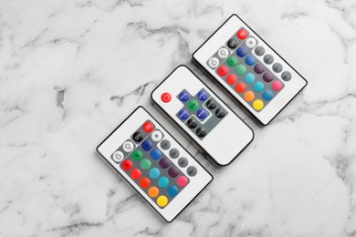 Photo of Remote controls on white marble table, flat lay