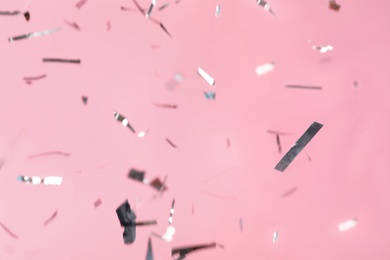 Photo of Shiny silver confetti falling down on pink background