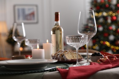 Photo of Christmas table setting with burning candles, appetizers and dishware in room