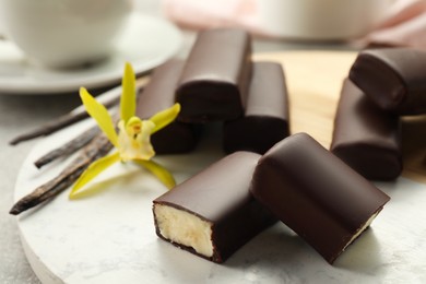 Photo of Glazed curd cheese bars, vanilla pods and flower on board, closeup