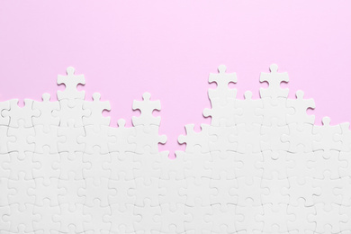 Photo of White puzzle on pink background, flat lay