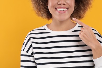 Photo of Woman showing her clean teeth on yellow background, closeup