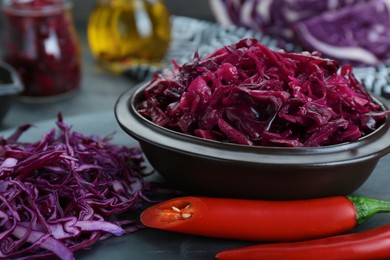 Photo of Tasty red cabbage sauerkraut and ingredients on grey table, closeup