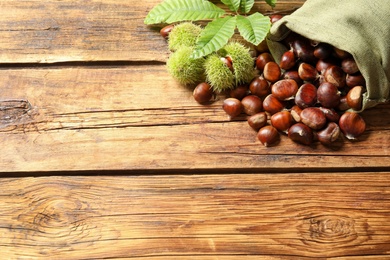 Photo of Fresh sweet edible chestnuts on wooden table, above view. Space for text