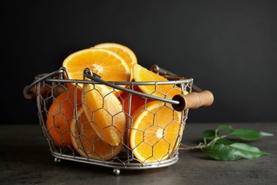 Photo of Fresh juicy oranges in basket on grey table