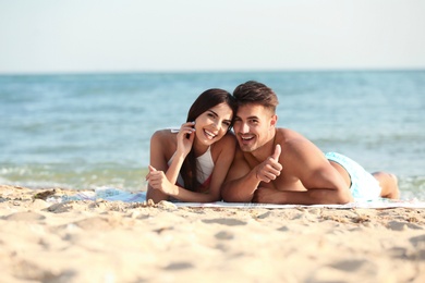 Photo of Happy young couple lying together on beach