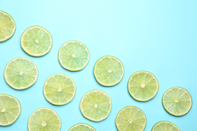 Photo of Fresh juicy lime slices on light blue background, flat lay. Space for text