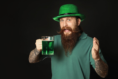 Photo of Bearded man with green beer on black background. St. Patrick's Day celebration