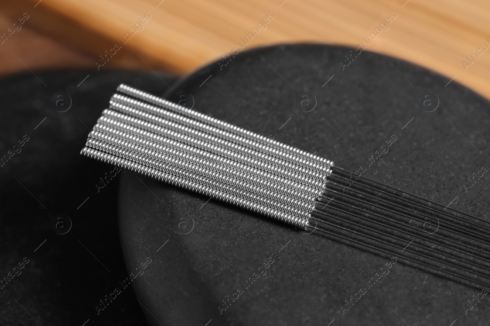Photo of Stone coaster with acupuncture needles on table, closeup
