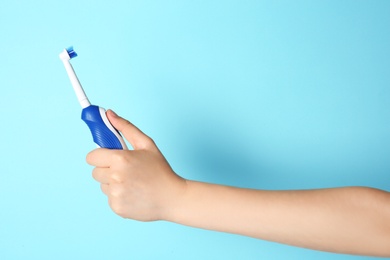 Photo of Woman holding electric toothbrush against color background