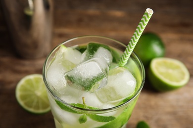 Photo of Delicious mojito and ingredients on wooden background, closeup