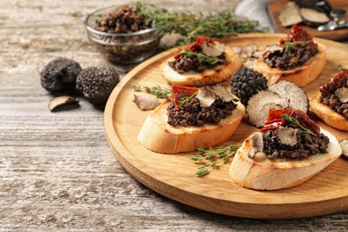 Photo of Delicious bruschettas with truffle sauce and sun dried tomatoes on wooden table. Space for text