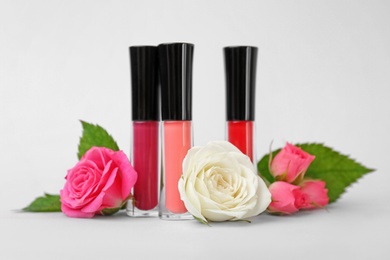 Photo of Lip glosses and flowers on light background