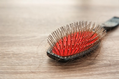 Photo of Brush with lost hair on wooden table. Alopecia problem