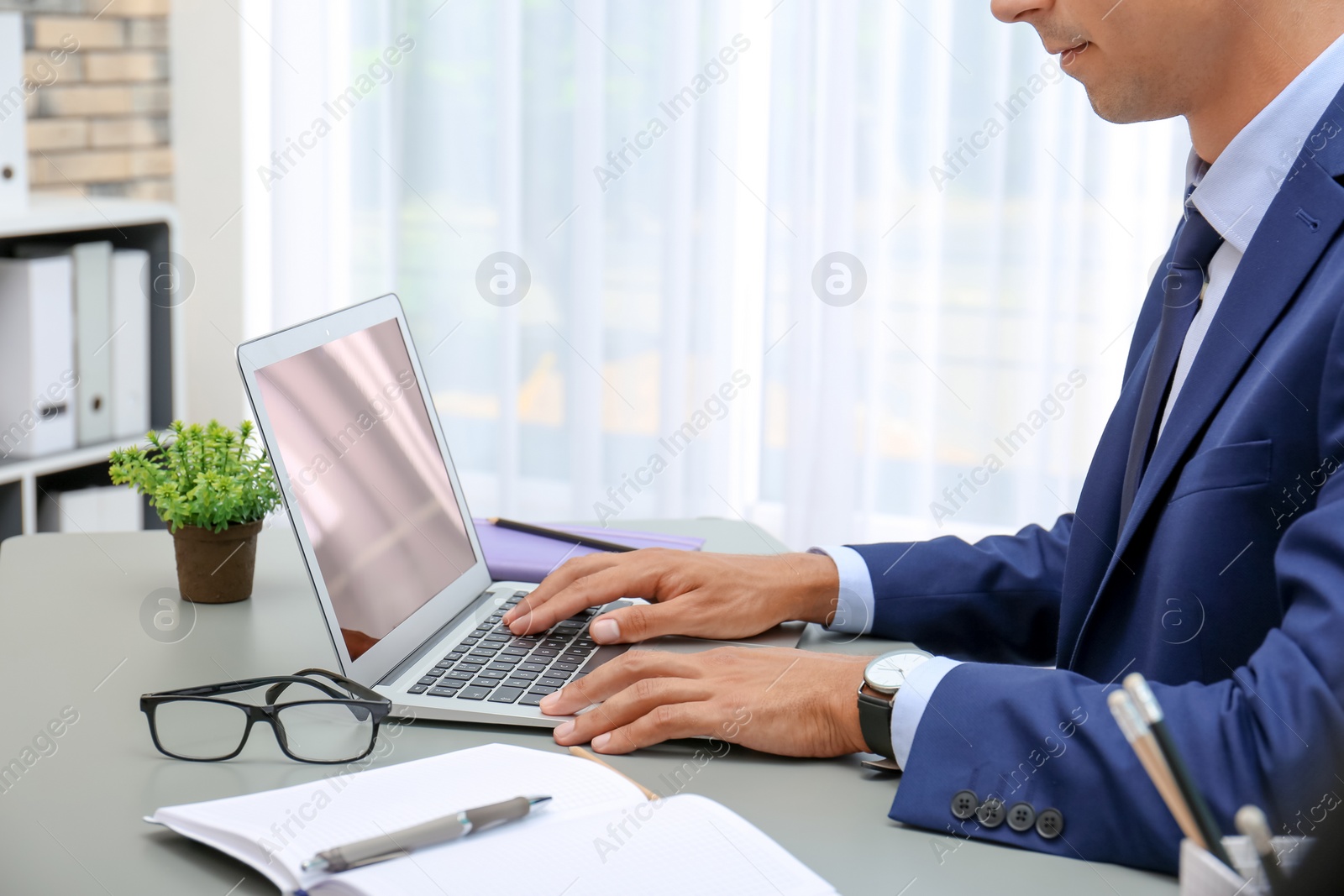 Photo of Man in office wear using laptop at table indoors