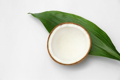 Photo of Half of fresh coconut and palm leaf on white background, top view