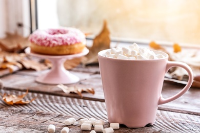 Photo of Composition with cup of hot cozy drink and autumn leaves on windowsill. Space for text